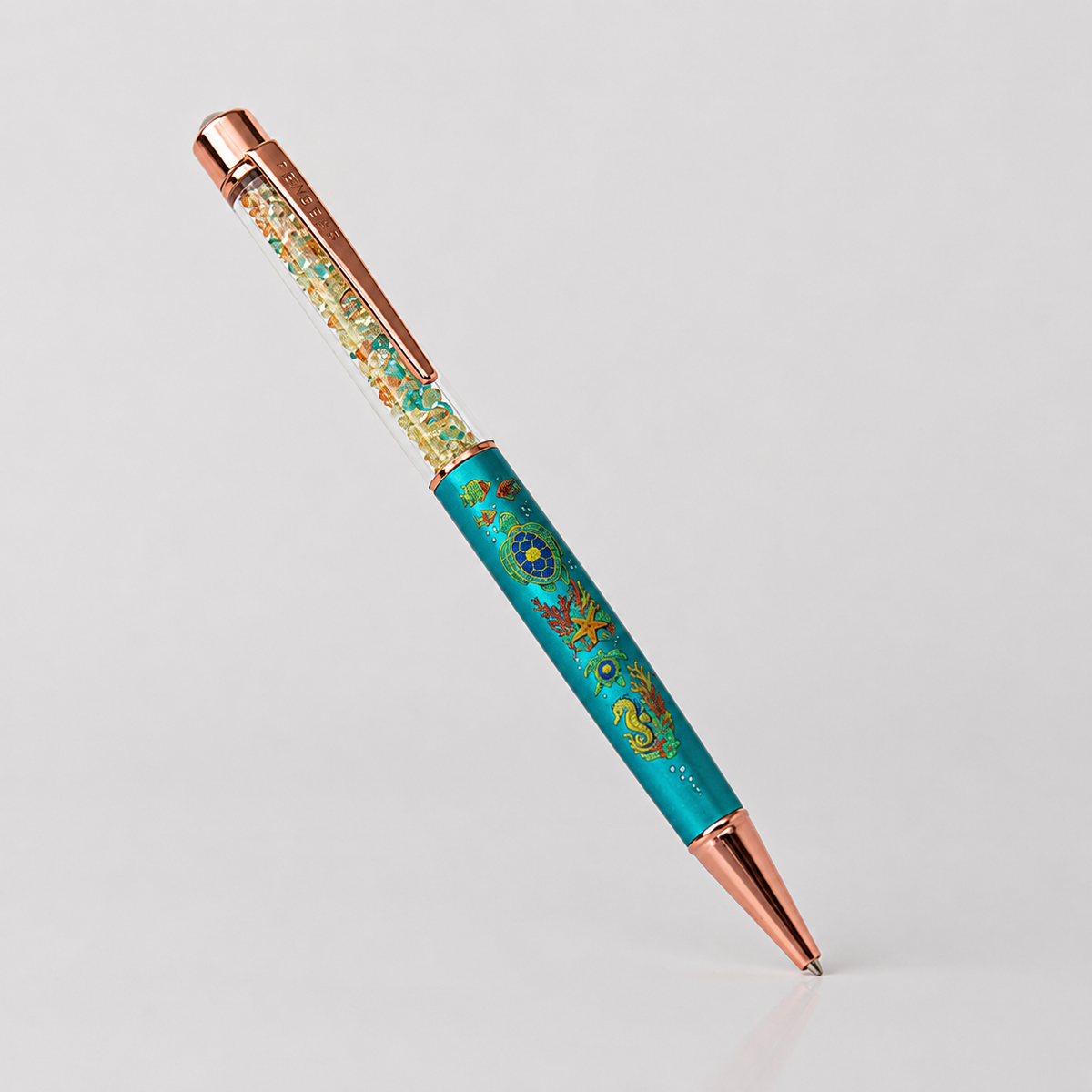 PenGems - Turtle Bay - crystal pen with a mosaic sea turtle, coral, and seahorse design on a turquoise barrel and rose gold hardware, on a plain white background.